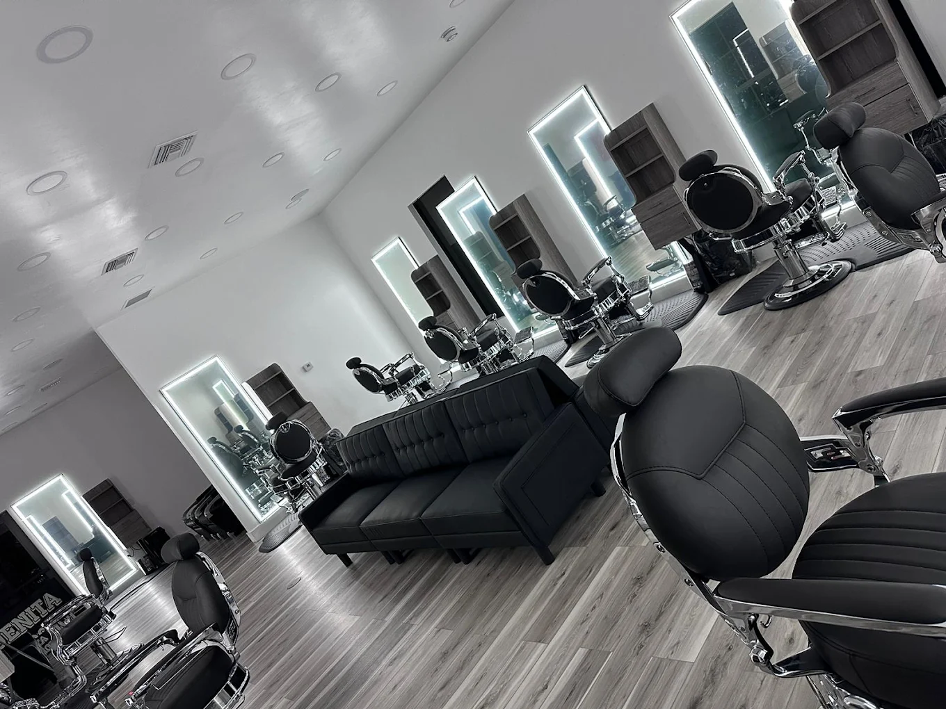 Interior de Quenita, con sillas de barbería y espejos iluminados